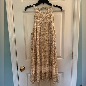 Sleeveless yellow and cream print sundress with lace details, missing a button.